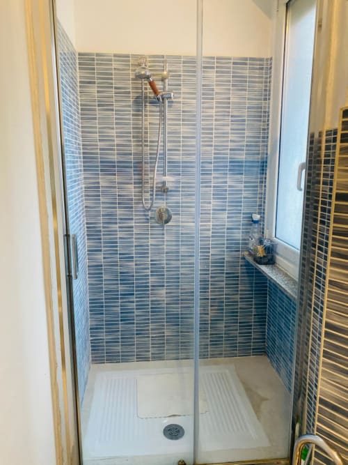 Modern shower enclosure with blue striped tile walls at Milano Underground BnB apartment in Milano, Italy