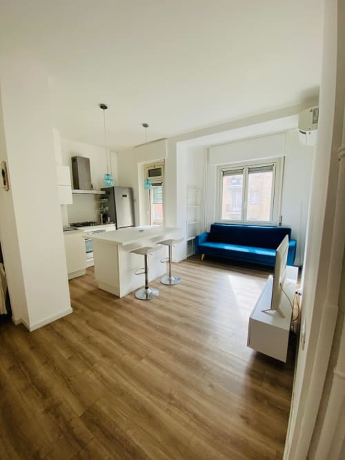 Modern Milano apartment with open-plan kitchen, island seating, and blue sofa in living area with wooden floors