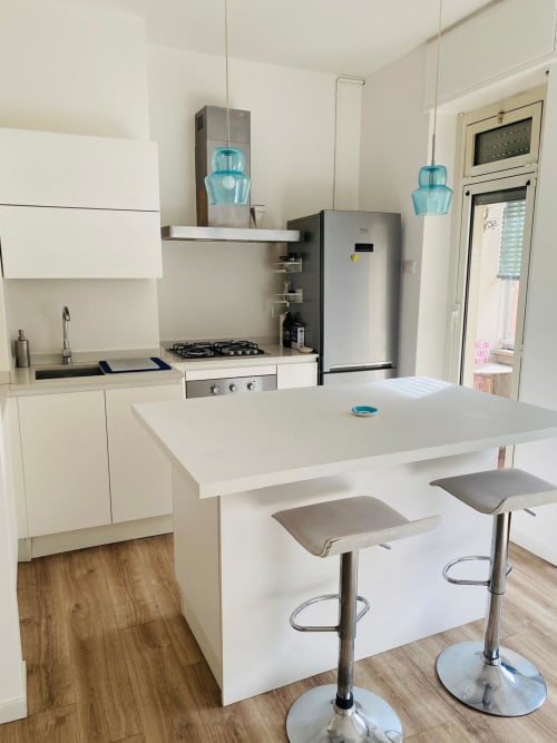 Modern white kitchen with island seating at Milano Underground BnB Milano apartment, featuring stainless steel appliances and