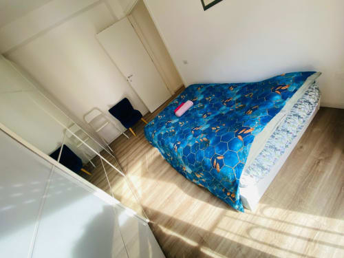Bright bedroom in Milano Underground BnB with blue patterned bedding, wooden flooring, white ceiling, and modern furnishings