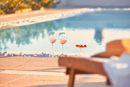 Due bicchieri di vino rosato sulla spiaggia sabbiosa di Villa Ceci, Andria Italia, con acqua turchese e lettini