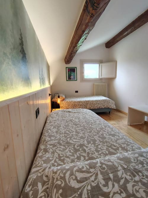 Accogliente camera matrimoniale in soffitta al B&B Monte Adone di Monzuno con travi di legno rustico, biancheria decorativa e illuminazione calda