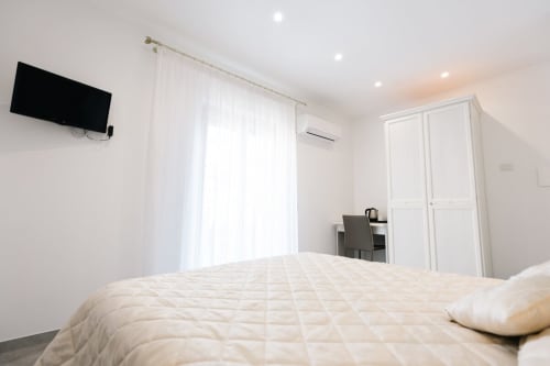 Modern bedroom at L'Amaranto B&B in Agerola with queen bed, flat-screen TV, and bright natural light