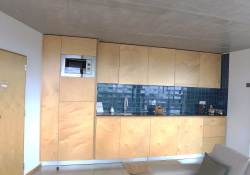 Modern kitchen in Casa A at Pera da Serra rural accommodation in Lousã, Portugal, featuring wooden cabinetry and teal tile