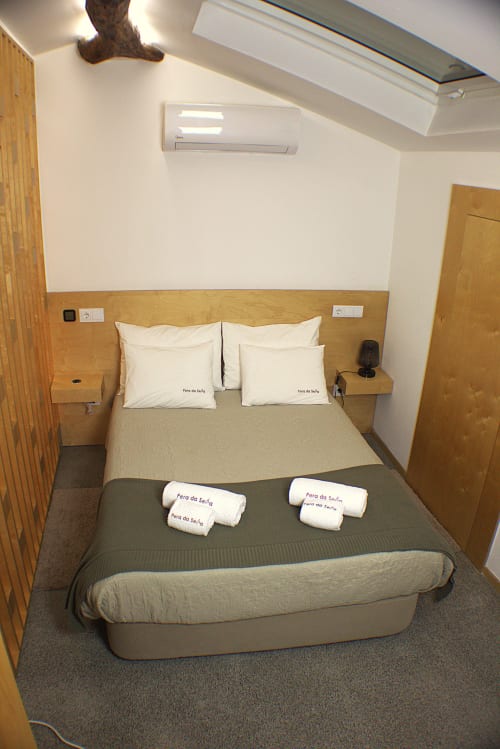 Cozy bedroom at Pera da Serra with queen bed, white pillows, wooden headboard, skylight, and air conditioning in Lousã,