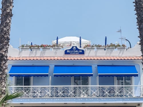Ingresso alle exclusive rooms di Blu Dalia con tende blu e balaustra ornamentale a Ischia, Italia
