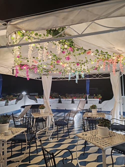 Elegante cena in terrazza a Bludalia B&B a Ischia con decorazioni floreali sospese e pavimenti decorati