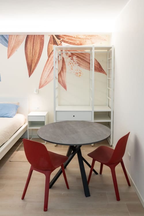 Suite Flavia Deluxe presso EQM Roma con tavolo rotondo, sedie rosse e decorazioni botaniche alle pareti