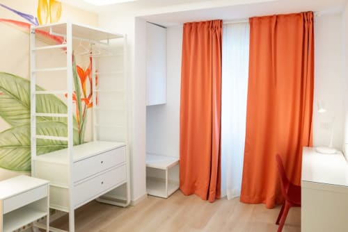 Suite Ottavia Deluxe presso l'EQM Roma con letto a baldacchino bianco, tende arancioni e arredi moderni