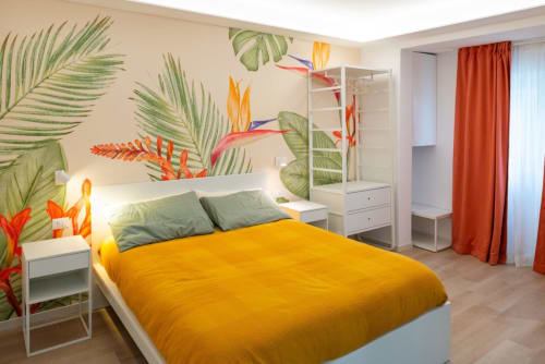 Camera Deluxe Suite Ottavia presso EQM Roma con murale tropicale, biancheria gialla, cuscini verdi e arredi bianchi moderni