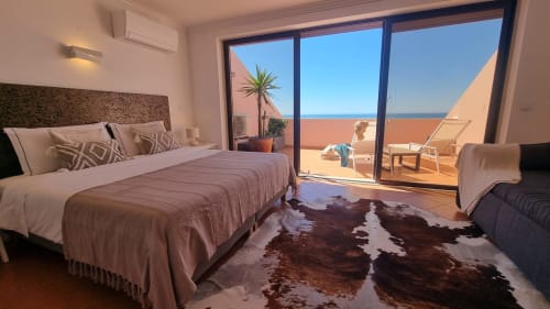 Quarto luminoso com cama de casal, terraço com vista para o mar e tapete de couro na King's House Ericeira, Portugal