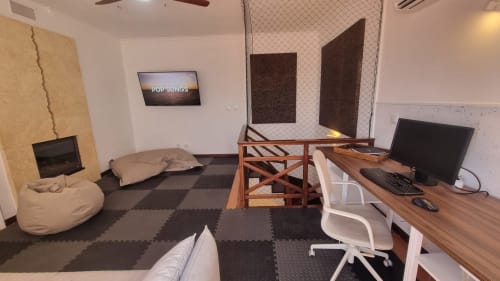 Espaço de trabalho moderno com secretária, computador, puf e painéis acústicos em King's House Ericeira Portugal