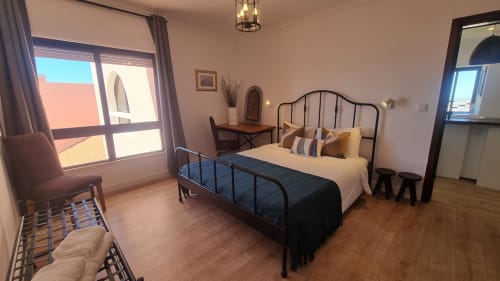 Quarto espaçoso no apartamento King's House Ericeira com cama de ferro forjado, varanda com vista para o mar, assoalho de madeira e design moderno