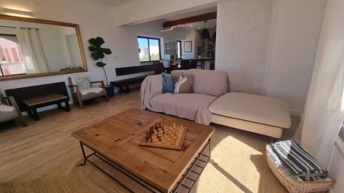 Sala de estar espaçosa em King's House Ericeira com sofá bege, mesa de café em madeira com tabuleiro de xadrez e vista para o mar