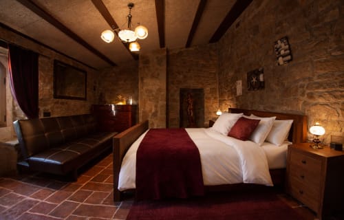 Habitación romántica con muros de piedra y vigas de madera en una fortaleza histórica