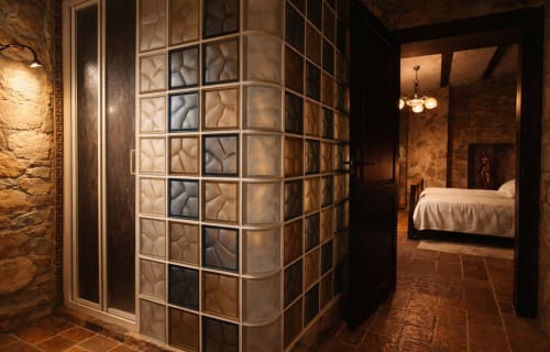 Stone bathroom with warm lighting beside a historic bedroom in a medieval fortress