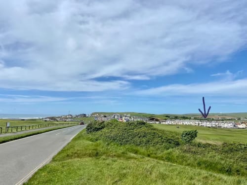 Rural coastal landscape near Exeter with green fields, white houses, and winding road under blue sky