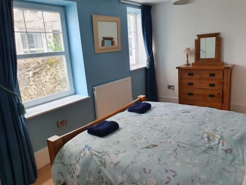 Spacious bedroom at 2 Doves Holiday Property in Exeter with blue walls, wooden furniture, and floral bedding