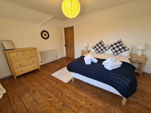 Spacious bedroom at 2 Doves Holiday Property in Exeter with wooden flooring, double bed, and traditional furnishings