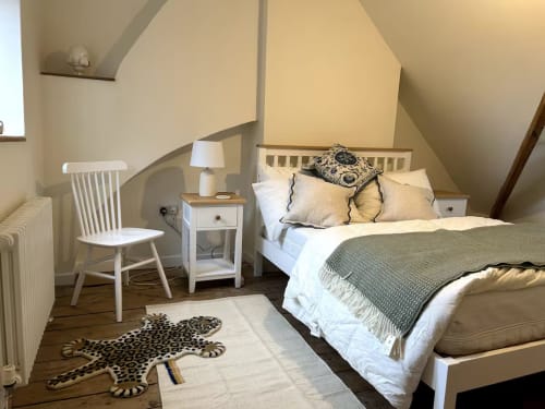 Cozy attic bedroom at 2 Doves Holiday Property in Exeter with white furniture, leopard rug, and sloped ceilings