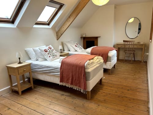 Spacious attic bedroom at 2 Doves Holiday Property, Exeter with twin beds, skylight, wooden beams, mirror and desk.
