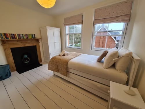 Bright bedroom at 2 Doves Holiday Property in Exeter with cream bed, fireplace, wooden floors and dual windows