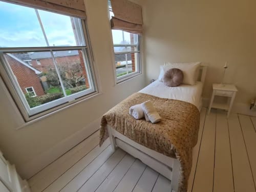 Bright bedroom at 2 Doves Holiday Property in Exeter with single bed, windows overlooking neighborhood, wooden flooring, and
