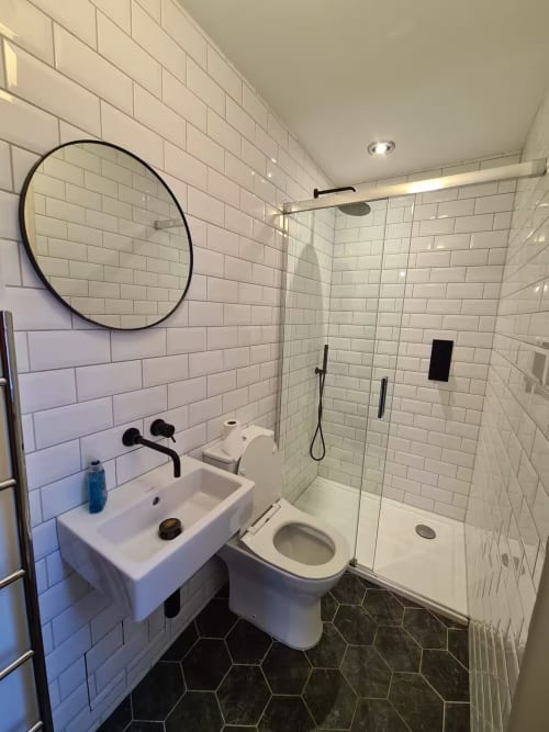 Modern bathroom at 2 Doves Holiday Property in Exeter with white subway tile, black fixtures, circular mirror, and walk-in