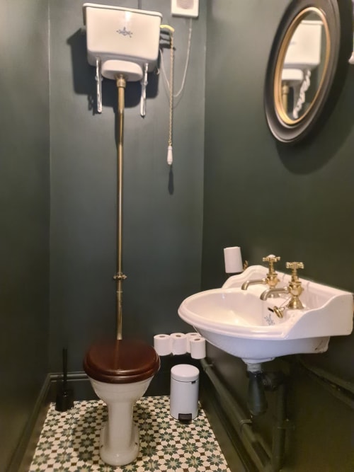 Vintage bathroom at 2 Doves Holiday Property, Exeter with pedestal sink, toilet, wall-mounted cistern and decorative mirror