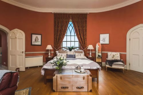 Elegant bedroom at 2 Doves Holiday Property in Exeter with burnt orange walls, wooden bed, and arched doorways