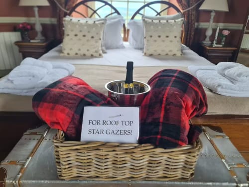 Luxury bedroom welcome basket at 2 Doves Holiday Property with champagne, red plaid blanket, and roof top stargazing note in