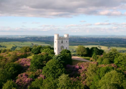 White castle tower surrounded by rhododendrons overlooking Devon countryside near Exeter
