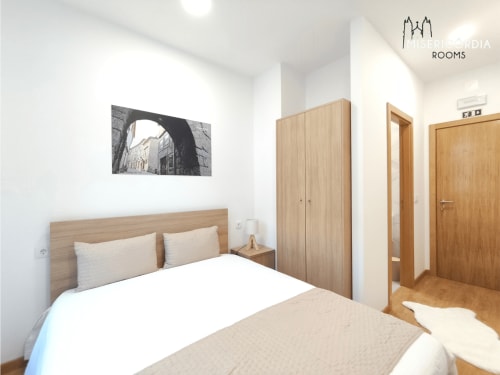 Quarto moderno da Coleção SM Stays em Guarda com cama de madeira, guarda-roupa e quadros com vista da cidade