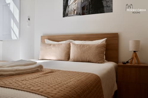 Quarto aconchegante na Misericórdia Rooms em Guarda com cama de madeira, roupa de cama bege e quadros com vista da cidade