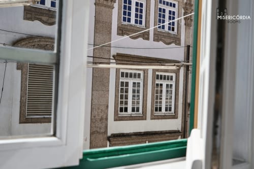 Vista do edifício histórico de pedra com janelas de moldura branca nas Salas da Misericórdia em Guarda, Portugal
