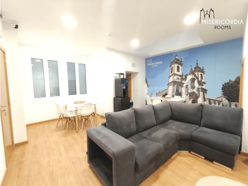 Moderna sala de estar com sofá cinzento, zona de refeições e mural da Catedral da Guarda na Coleção SM Stays Portugal