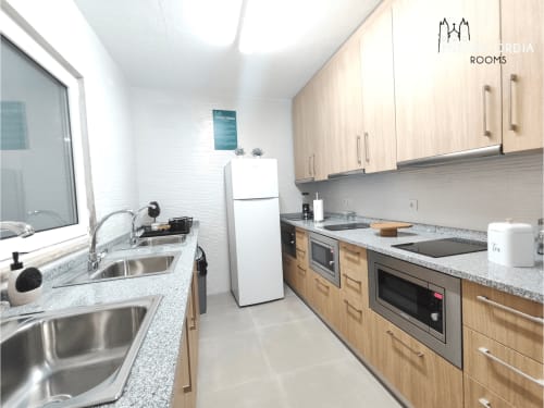 Cozinha moderna com armários em madeira, bancadas em granito e eletrodomésticos em aço inoxidável no hotel SM Stays Collection