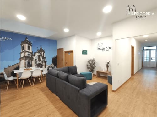 Área comum da Miserícórdia em Guarda com assentos, espaço de refeições e mural da catedral