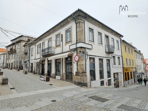 Edifício histórico de esquina em Guarda, Portugal com fachada branca e creme, arquitetura tradicional e lojas no piso térreo