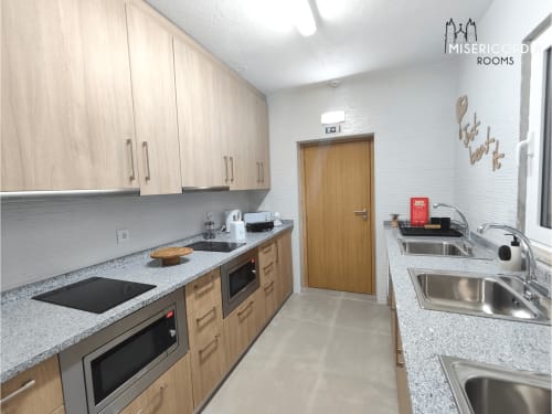 Kitchenette moderna em Torre dos Ferreiros em Guarda com armários em madeira clara, bancadas em granito e pias em aço inoxidável