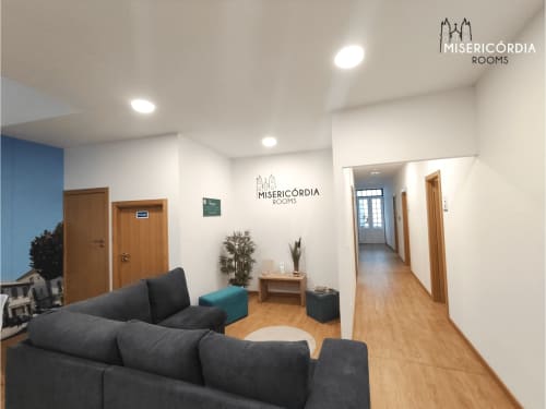 Sala comum Portas Del Rei na SM Stays Collection Guarda com sofá preto moderno, portas em madeira e design contemporâneo