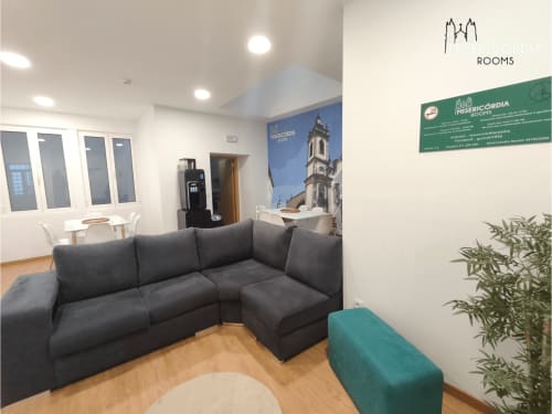 Sala de estar moderna no quarto Alameda em Guarda com sofá secional escuro, assoalhos em madeira e vista da cidade na SM Stays Collection