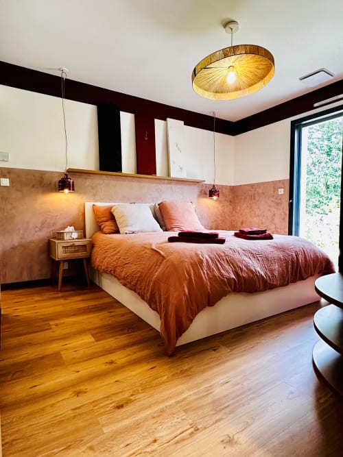 Chambre moderne du Cottage L'instant à Amboise aux murs en terracotta, lit queen-size, parquet, luminaires suspendus et jardin