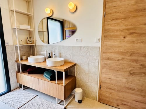 Salle de bain moderne avec deux vasques blanches, meuble en bois, miroir chauffant et dosseret carrelé à L'Instant Cottage