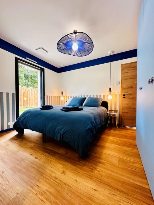 Chambre moderne à L'Instant Cottage à Amboise avec mur à rayures bleues, parquet et vue sur le jardin