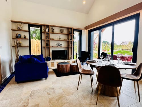 Séjour et salle à manger ouverts et modernes à L'Instant Cottage avec canapé en velours bleu, vue sur le jardin par grandes fenêtres