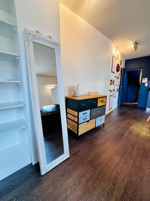 Couloir de gîtes moderne à L'instant Clos Lucé avec commode en bois, miroir encadré blanc et porte d'entrée bleue