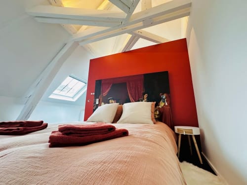 Chambre mansardée moderne à L'instant Clos Lucé à Amboise avec mur accent rouge, poutres inclinées et literie crème avec linge de lit bordeaux