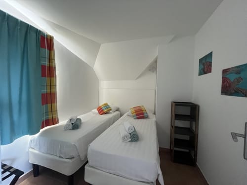 Lits jumeaux avec coussins colorés dans la chambre Tobago avec vue mer premium aux Tropic Appartements, Sainte-Anne