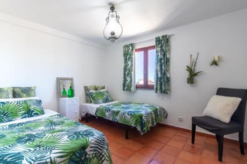 Quarto Duplo na Villa Principezinho com roupa de cama estampada de folhas tropicais, piso em terracota e decoração botânica em Portugal